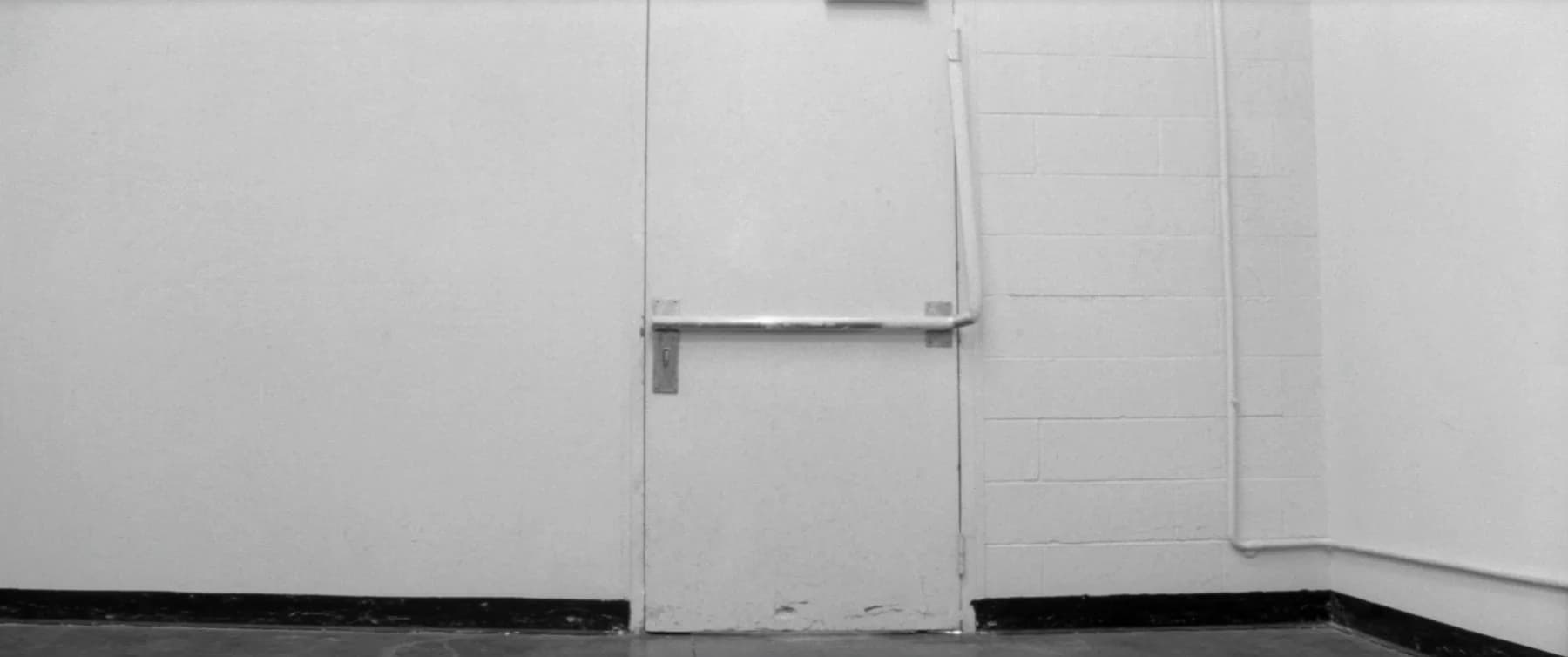 The inside face of a plain service door in an empty back corridor, photographed square-on